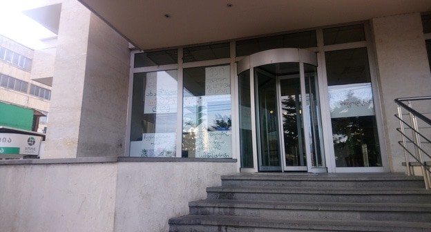 Здание министерства по делам беженцев Грузии с плакатами протестующих за стеклом. Фото Беслана Кмузова для "Кавказского узла".