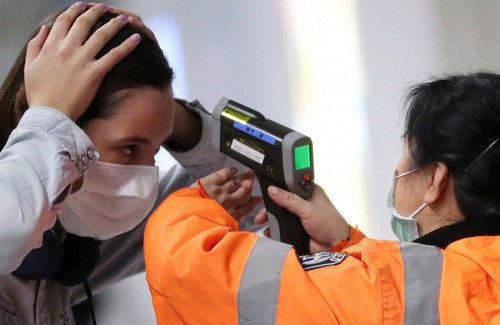 Пассажир, прибывающий в международный аэропорт Гонконга, проверил свою температуру. Фото: Reuters / Hannah McKay