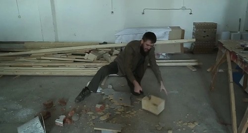 Чингиз Ахмадов ударами молотка разбивает кирпичи, деревянную столешницу, а также оставляет заметные вмятины на металлическом ведре и строительной каске. Стоп-кадр видео Instagram https://www.instagram.com/p/B9TZgN4IXm4/