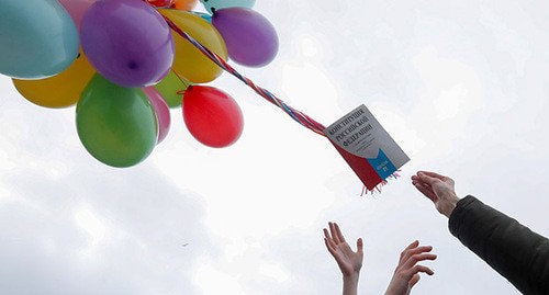 Руки активистов и Конституция РФ, привязанная к воздушным шарам. Фото: REUTERS/Anton Vaganov