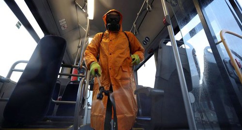 Сотрудник в защитном снаряжении распыляет дезинфицирующее средство для дезинфекции пассажирского автобуса в Тбилиси. Фото: REUTERS/Irakli Gedenidze
