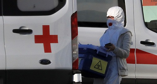 Медицинский работник в защитном костюме возле машины скорой помощи. Фото: REUTERS/Tatyana Makeyeva