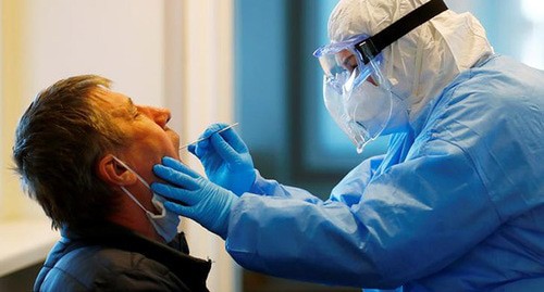 Медицинский работник берет тест на вирус у пациента. Латвия, март 2020 г. Фото: REUTERS/Ints Kalnins