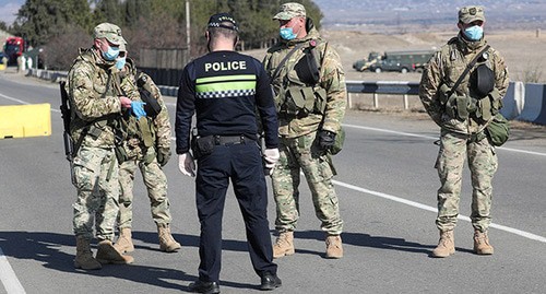 Грузинские военнослужащие и полицейский в защитных масках стоят на страже на контрольно-пропускном пункте. Грузия, Марнеули, март 2020 г. Фото: REUTERS/Irakli Gedenidze
