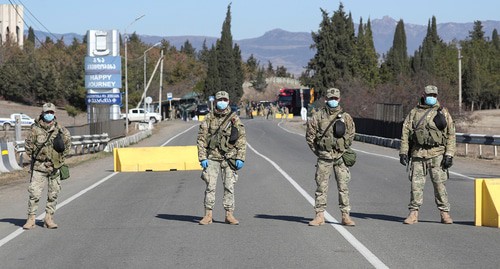 Грузинские военнослужащие в защитных масках стоят на страже на контрольно-пропускном пункте после того, как власти ужесточили меры по предотвращению распространения коронавирусной болезни (COVID-19) в Марнеули близ Тбилиси, Грузия, 23 марта 2020 года. REUTERS/Ираклий Геденидзе