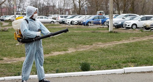 Человек в защитной одежде проводит дезинфекцию. Фото: REUTERS/Eduard Korniyenko