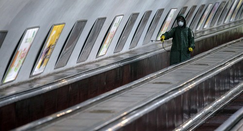 Сотрудник в защитном снаряжении едет на эскалаторе, распыляя дезинфицирующее средство для дезинфекции станции метро в Тбилиси, Грузия, март 2020 года. REUTERS/Ираклий Геденидзе