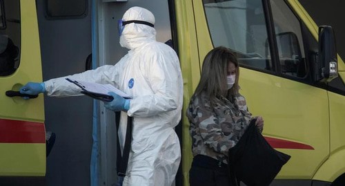 Медицинский работник в защитном костюме и пациент в защитной маске возле машины скорой помощи. Россия, апрель 2020 года. Фото: REUTERS/Tatyana Makeyeva