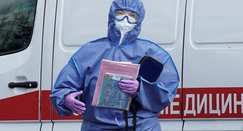 Медицинский работник в защитном костюме возле машины скорой помощи. Фото: REUTERS/Tatyana Makeyeva
