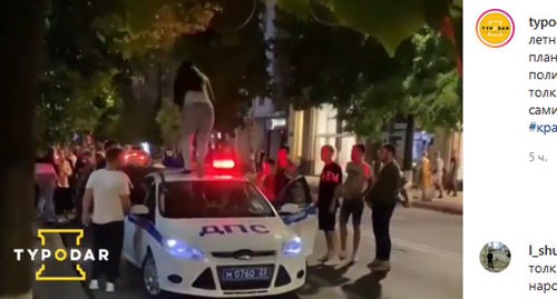 Девушка пробегает по крыше полицейской машины в Краснодаре. Кадр видео, опубликованного в Instagram-паблике "Туподар" https://www.instagram.com/p/CBIHbq-gKWu/