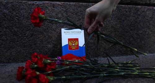 Активист возлагает цветы к копии российской Конституции во время акции протеста против одобрения парламентом России поправок к Конституции. Фото: REUTERS/Anton Vaganov