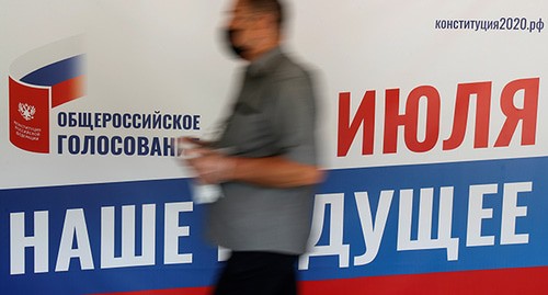 Человек на фоне плаката. Фото: REUTERS/Maxim Shemetov