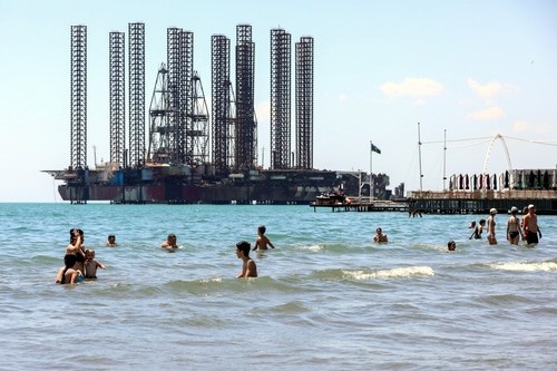 Люди купаются на пляже неподалеку от нефтяных вышек. Баку, 8 августа 2020 года. Фото Азиза Каримова для "Кавказского узла".