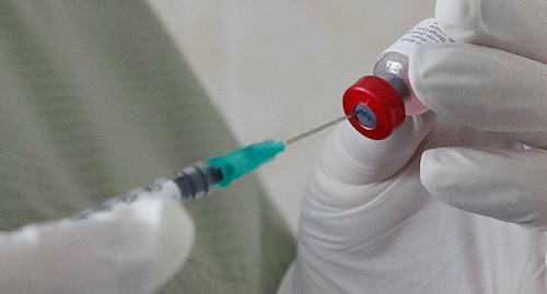 Медицинский работник держит шприц и вакцину. Фото: REUTERS/Valentyn Ogirenko