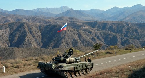 Военнослужащие российских миротворческих сил стоят рядом с танком у границы с Арменией, после подписания соглашения о прекращении военного конфликта  в районе Нагорного Карабаха, 10 ноября 2020 года. Фото : REUTERS/Francesco Brembati
