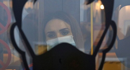 Девушка смотрит в окно, на котором нарисован силуэта человека в медицинской маске. 1 декабря 2020 г. Фото: REUTERS/Eduard Korniyenko