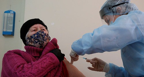 Медицинский работник делает прививку пожилой женщине. Фото: REUTERS/Eduard Korniyenko