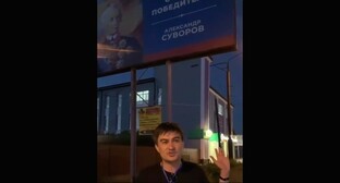  Адлер Туркменов на фоне возмутившего его плаката с изображением Суворова. Стопкадр из видео в в Telegram-канале "Многонационал" https://t.me/mnogonazi/6223. 