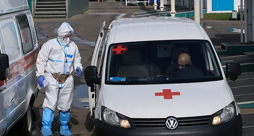 Машины скорой помощи и медицинский работник в защитном костюме. Фото: REUTERS/Наталья Макеева