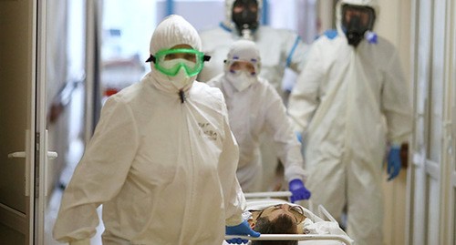 Медицинские работники в защитных костюмах рядом с пациентом. Фото: REUTERS/Kirill Braga
