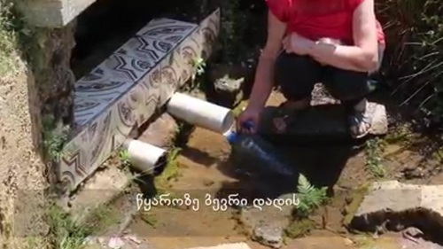 Жительница села Очхамури набирает воду из источника. Стопкадр из видео на странице https://batumelebi.netgazeti.ge/news/416076/