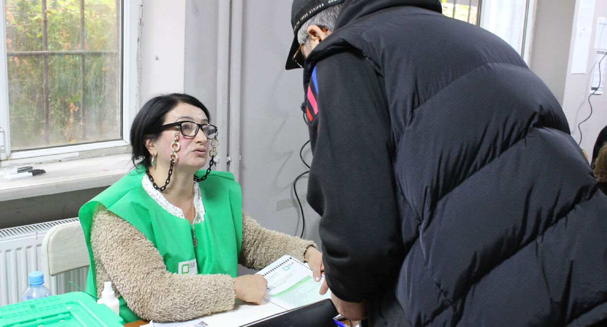 Представитель участковой избирательной комиссии объясняет избирателю, как голосовать по новой электронной системе. Тбилиси, 26 октября 2024 г. Фото Инны Кукуджановой для "Кавказского узла"