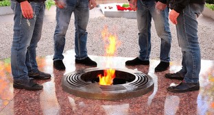 Мужчины стоят у Вечного огня. Иллюстрация создана «Кавказским узлом» с помощью ИИ в программе Photoshop
