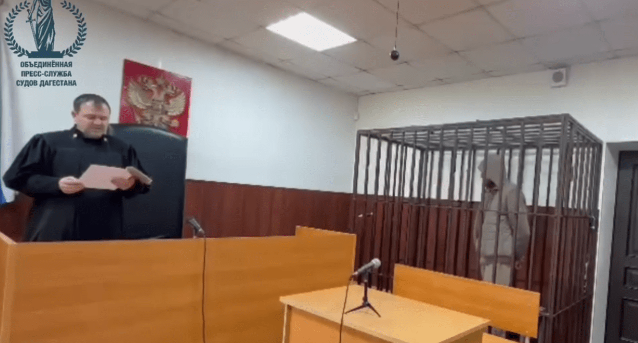 Судья и арестованный в зале суда. Стоп-кадр видео Telegram-канала "Фемида Дагестана" от 12.04.25, https://t.me/Femida_Dagestana/67.
