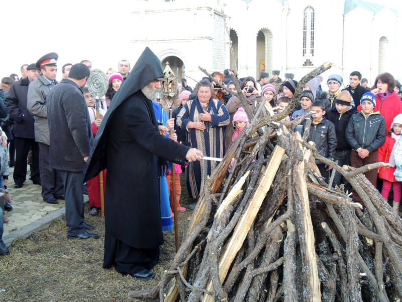 архиепископ Паргев Србазан зажигает костёр свечой из церкви.